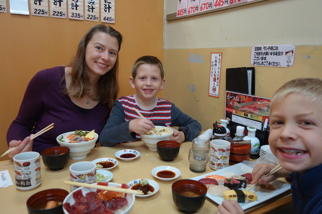 Mom and two boys eating sushi in Japan.