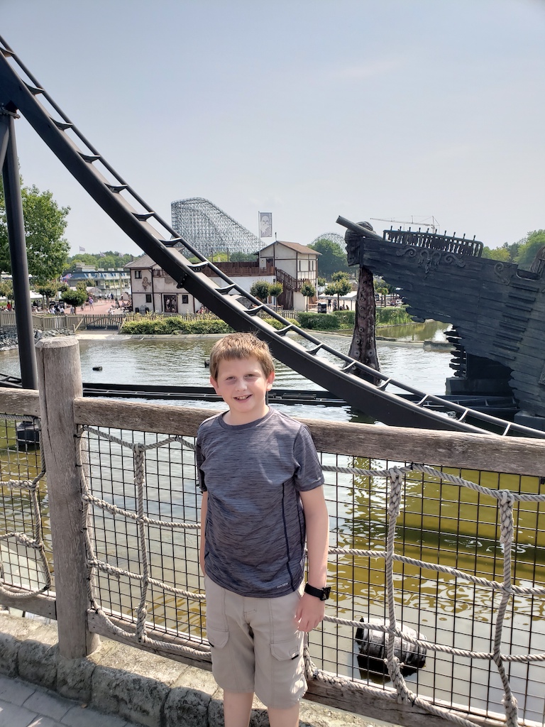 Boy standing near rollercoasters at Heide Park in Soltau, Germany.