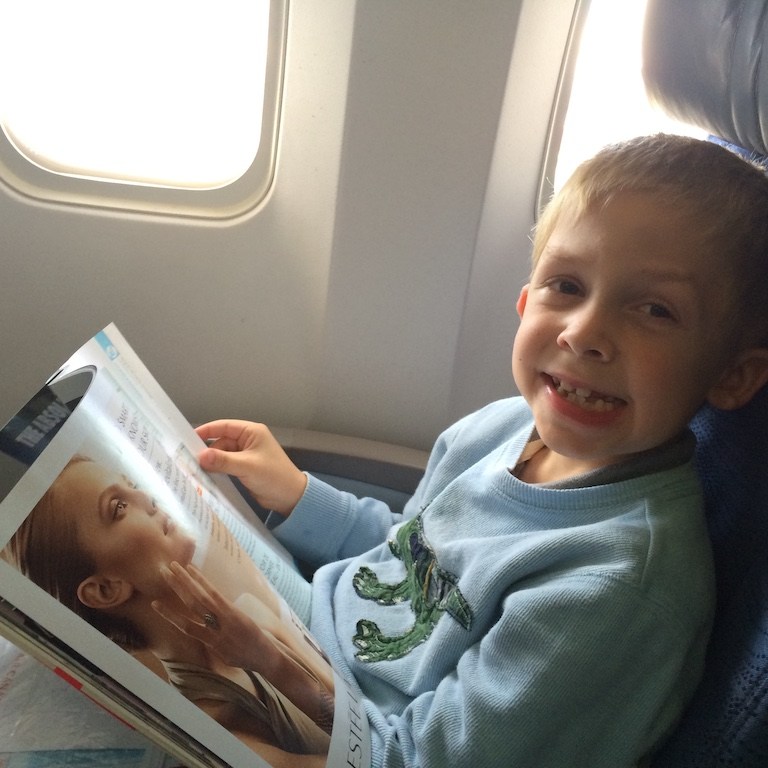 Boy reading a magazine on an airplane.