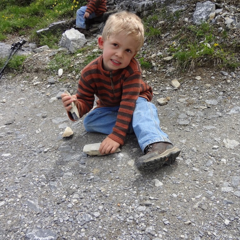 Boy playing with rocks while taking a break from hiking.