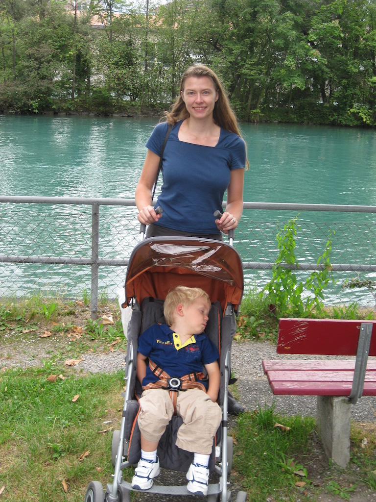 Mom with sleeping son by a river in Switzerland.