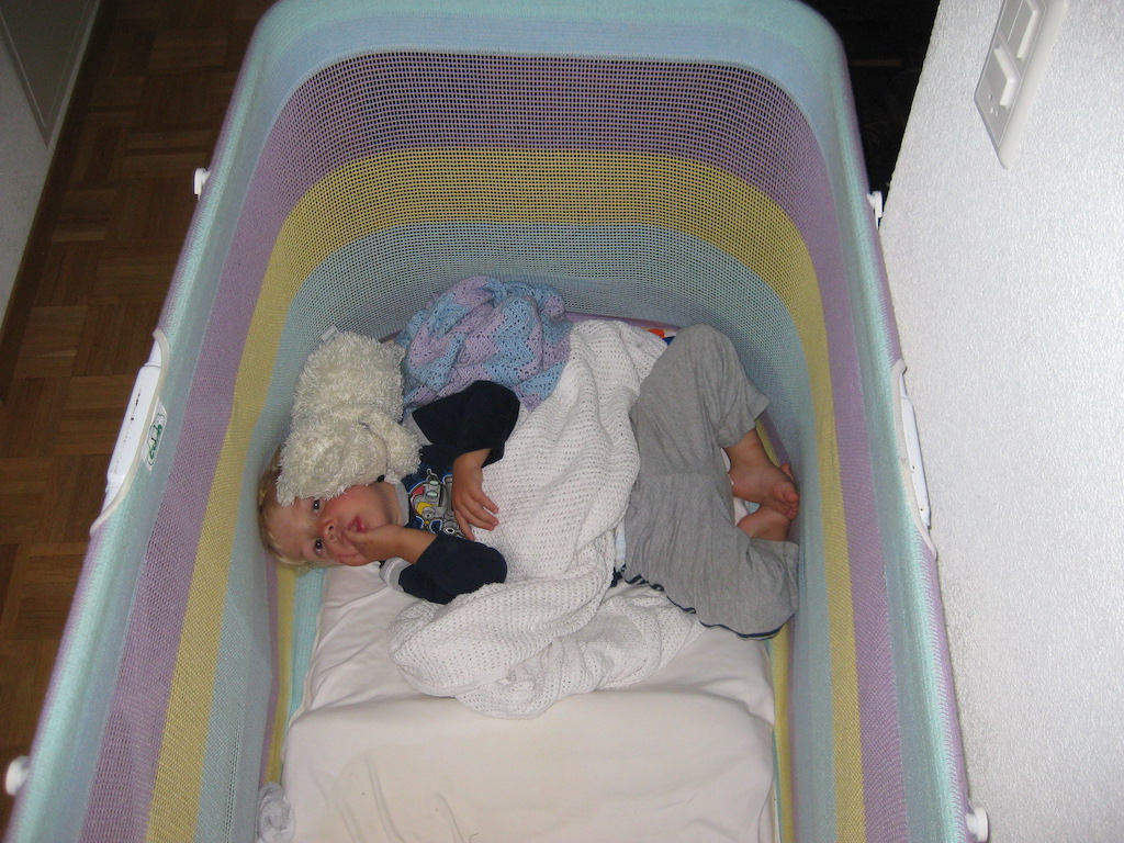 Toddler sleeping in a portable crib.