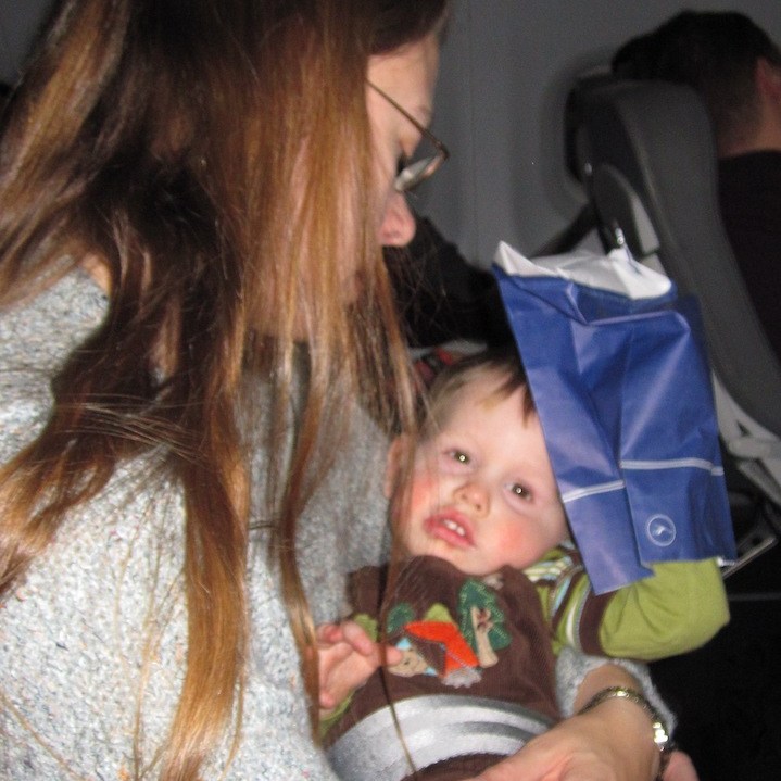 Boy playing with a barf bag on an airplane.