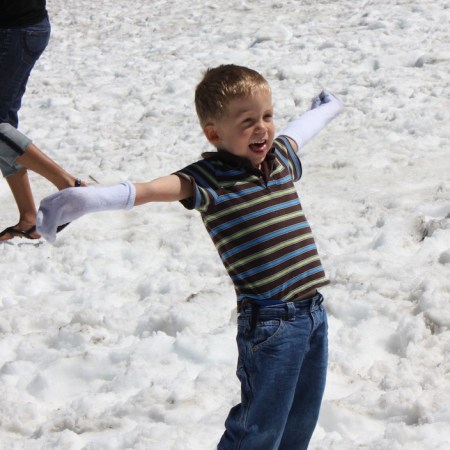 Boy enjoying makeshift gloves while playing in the summer snow.