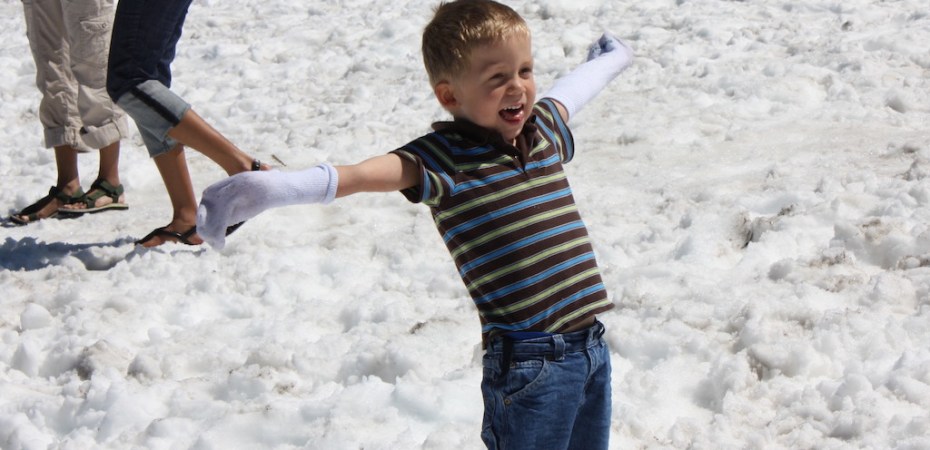 Boy enjoying makeshift gloves while playing in the summer snow.