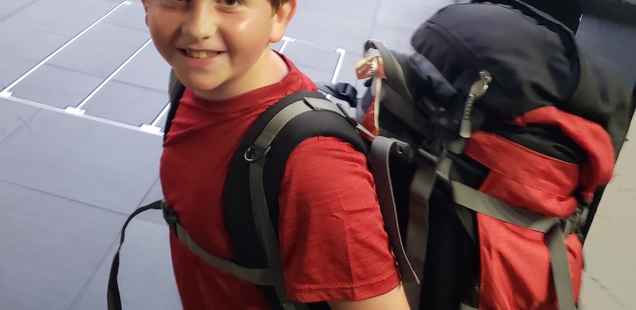 Boy carrying a gigantic bag.