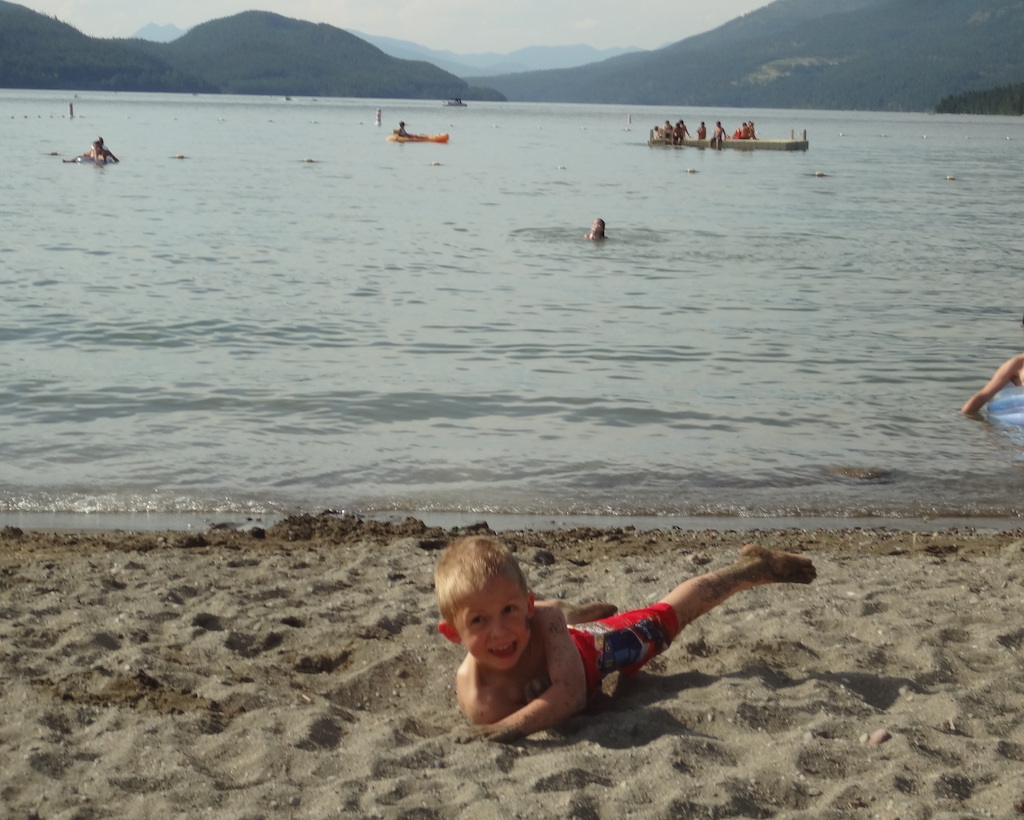 Boy rolling in the sand at the beach.