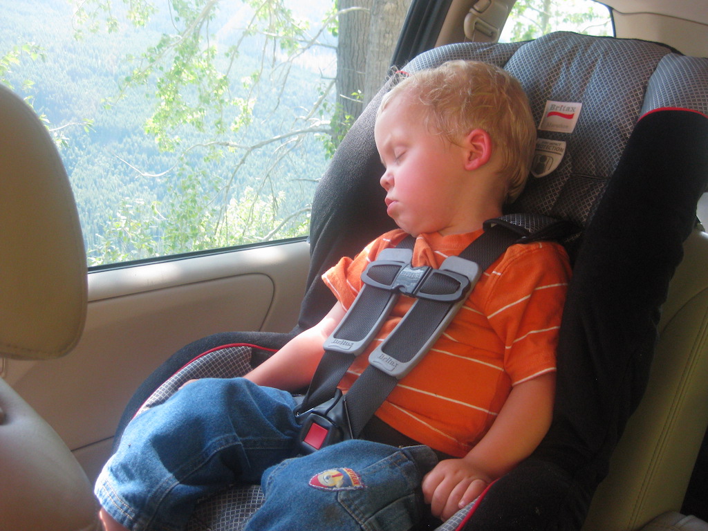 Boy sleeping in a car seat while traveling.