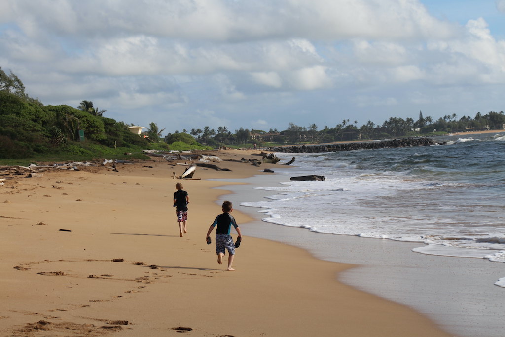 Two children running on a beach in Kauai, Hawaii.